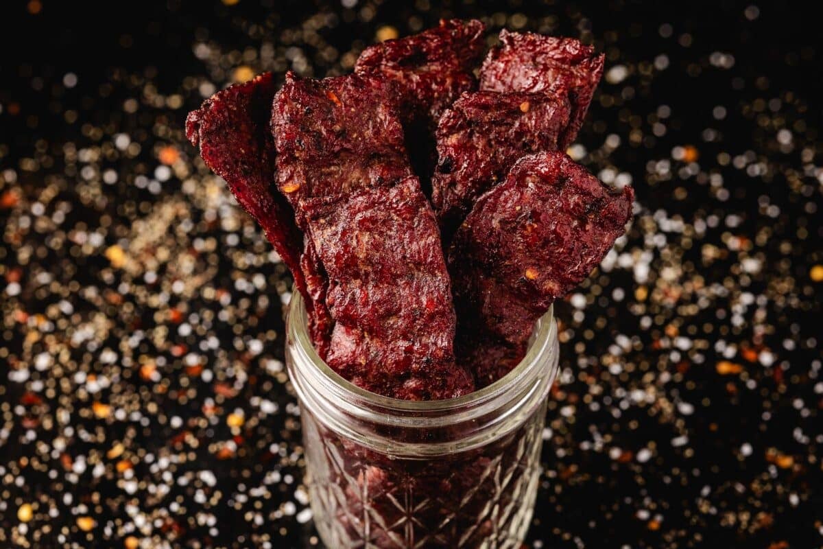 Sticks of dehydrated ground beef in a glass jar.