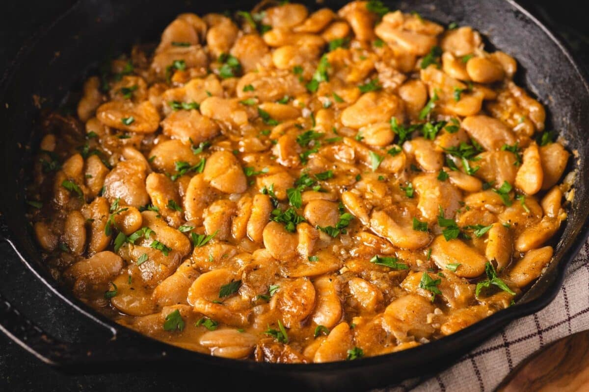 Cooked butter beans in a cast iron skillet garnished with parsley.