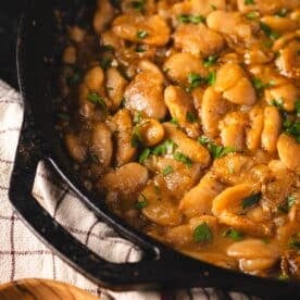 Cooked butter beans in a cast iron skillet sitting on a cloth napkin.