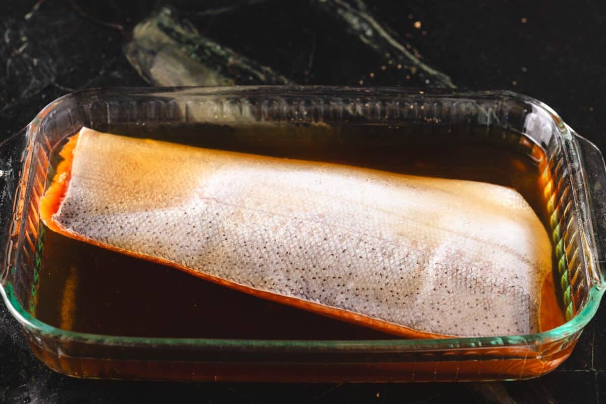 A fish fillet brining in a baking dish.