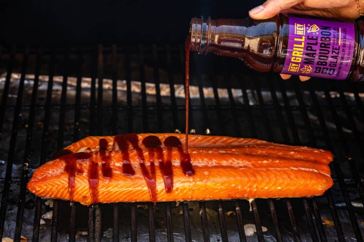 A trout fillet on the smoker being glazed with sauce.