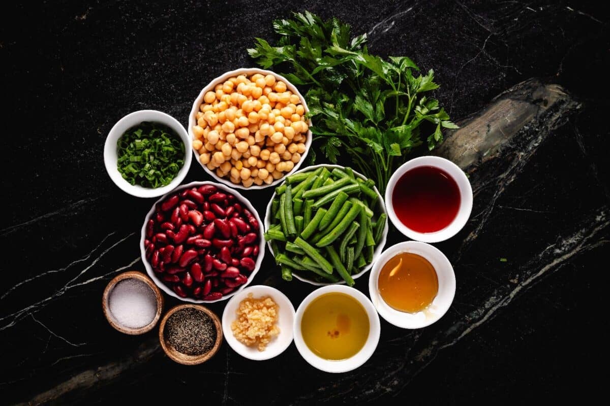 Salad ingredients in individual bowls grouped together on a marble surface.