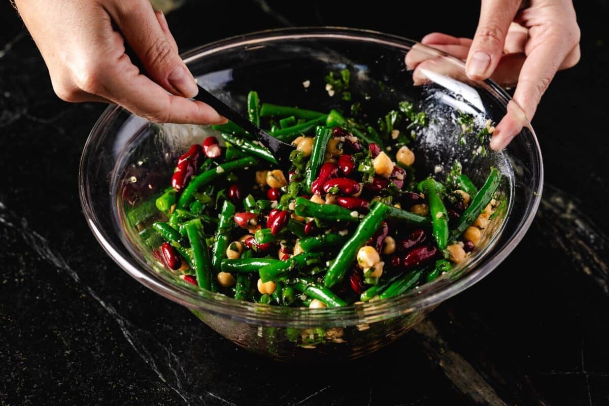 Salad in a glass bowl being stirred with a spoon.