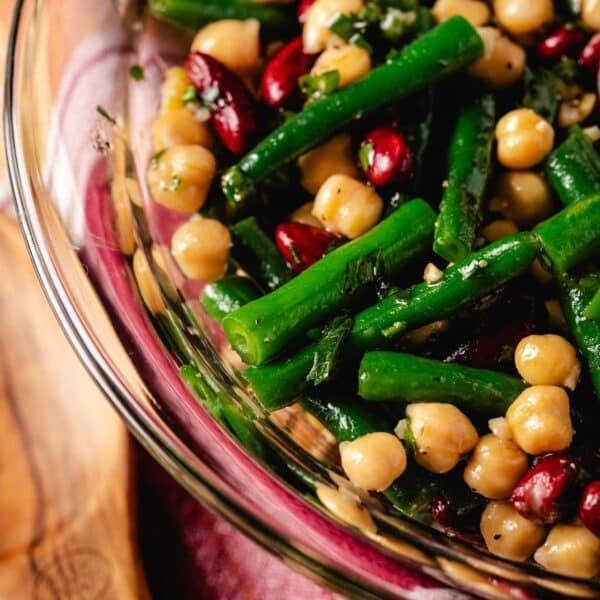 A salad of green beans, kidney beans, and chickpeas in a clear glass bowl.