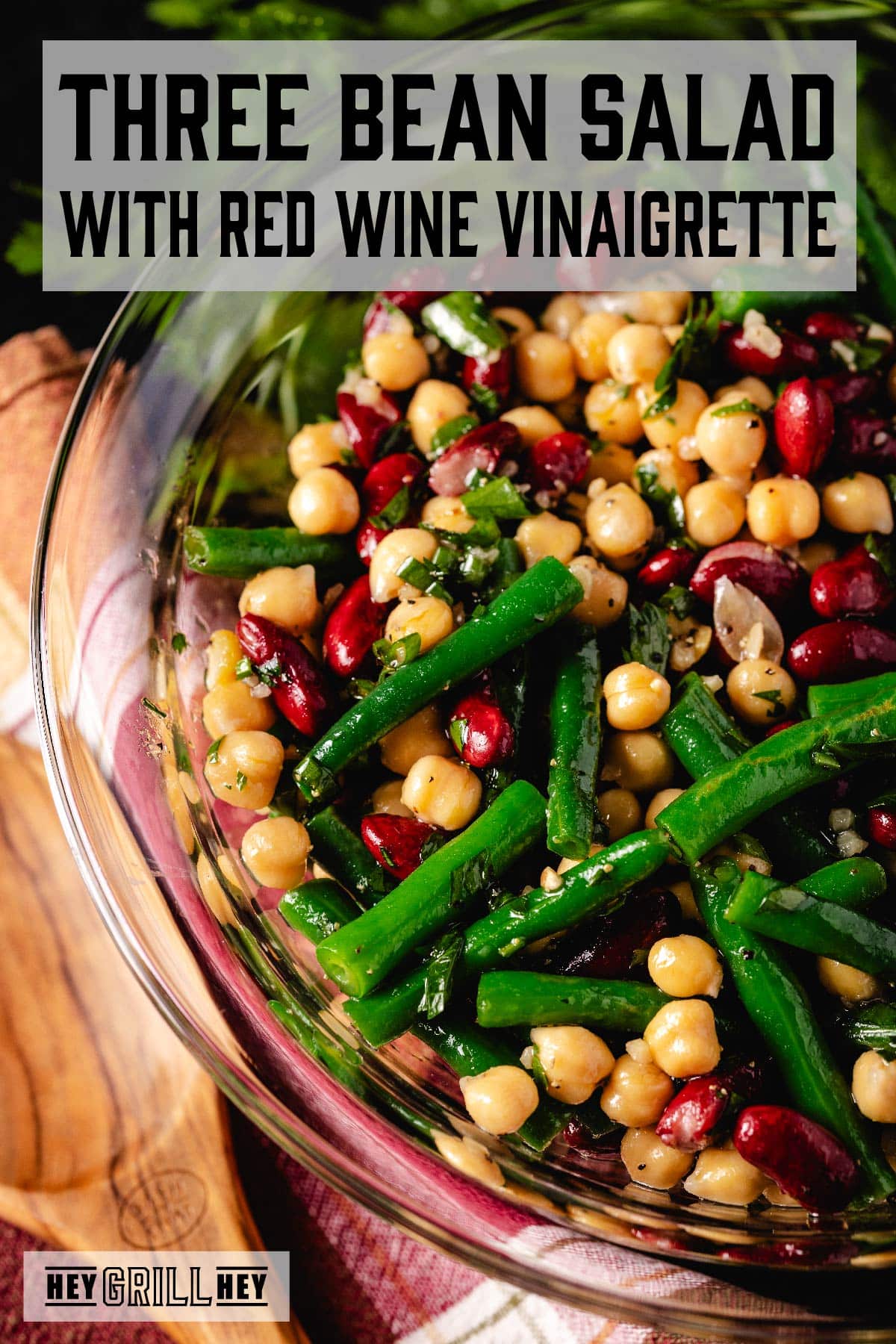 A salad of green beans, kidney beans, and chickpeas in a clear glass bowl. The text overlay reads "Three Bean Salad with Red Wine Vinaigrette" at the top, and "Hey Grill Hey" at the bottom.