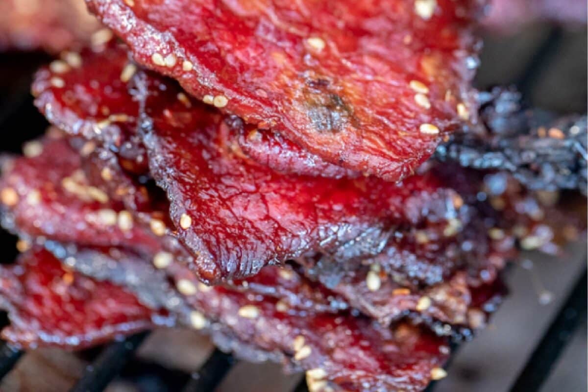 Jerky slices piled on a wire drying rack.