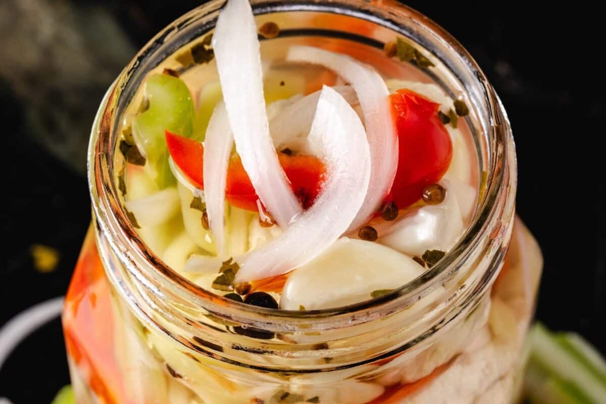 A close up shot of a glass jar filled with giardiniera.