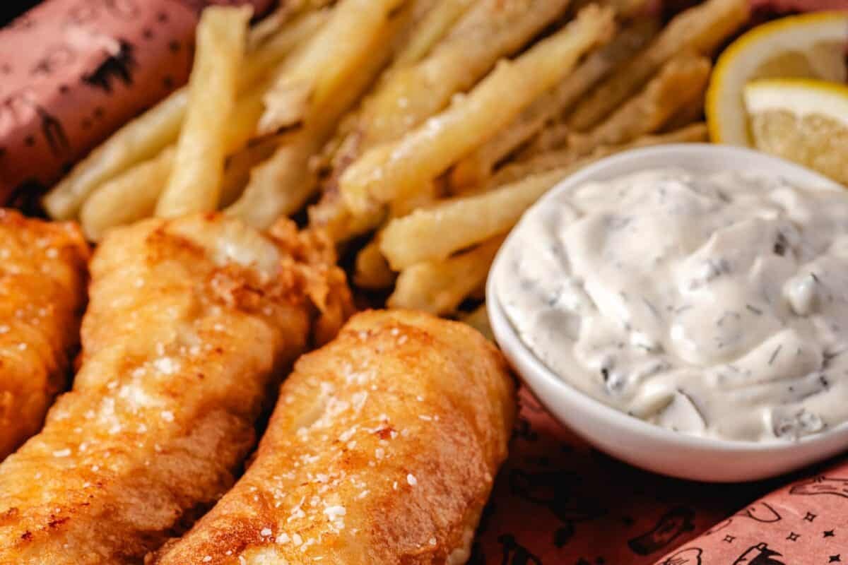 Fish and French fries next to a bowl of dip.