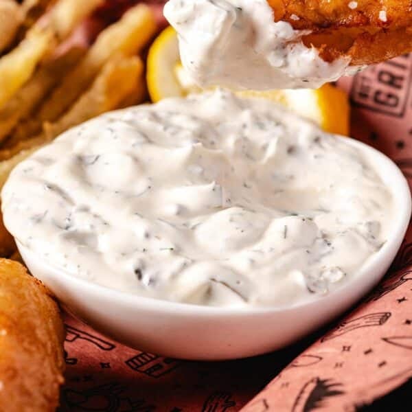 A white bowl of tartar sauce in butcher paper with French fries.