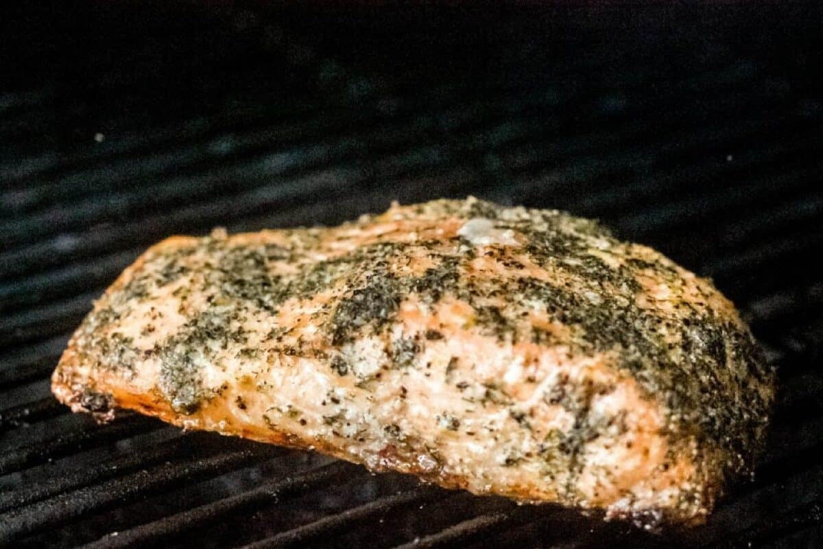 A seasoned fish fillet sitting on grill grates.