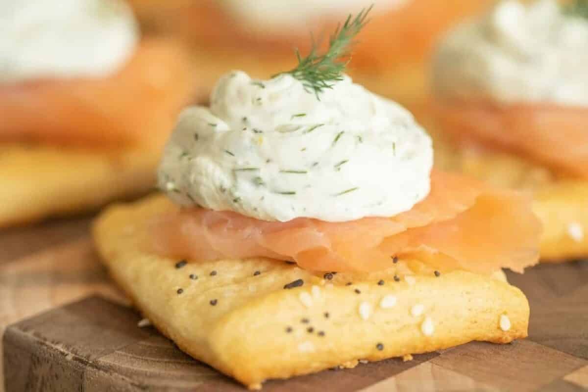 Crackers on a table topped with sliced salmon and cream cheese.