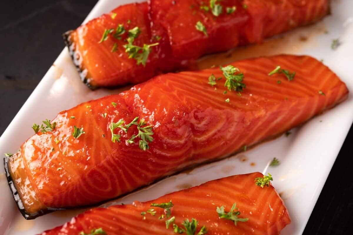 Smoked salmon fillets on a white plate garnished with herbs.