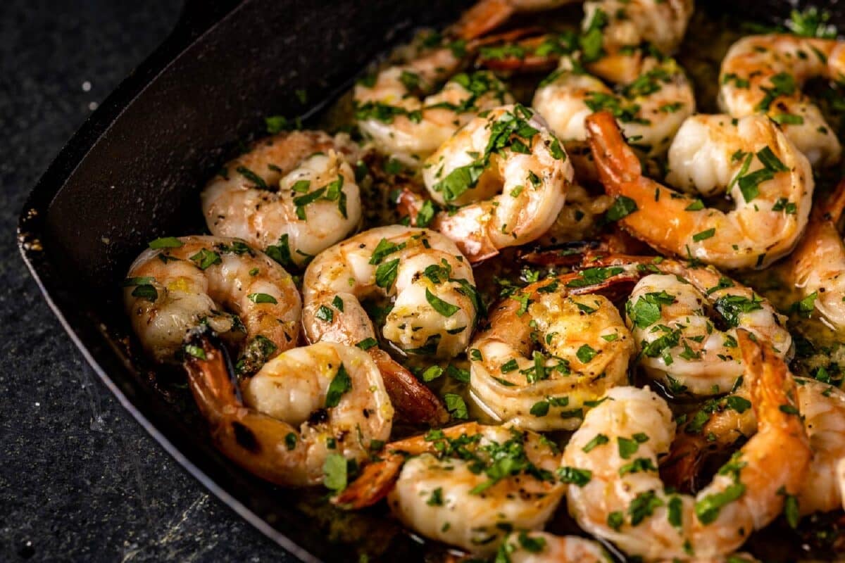 A black plate full of grilled shrimp.