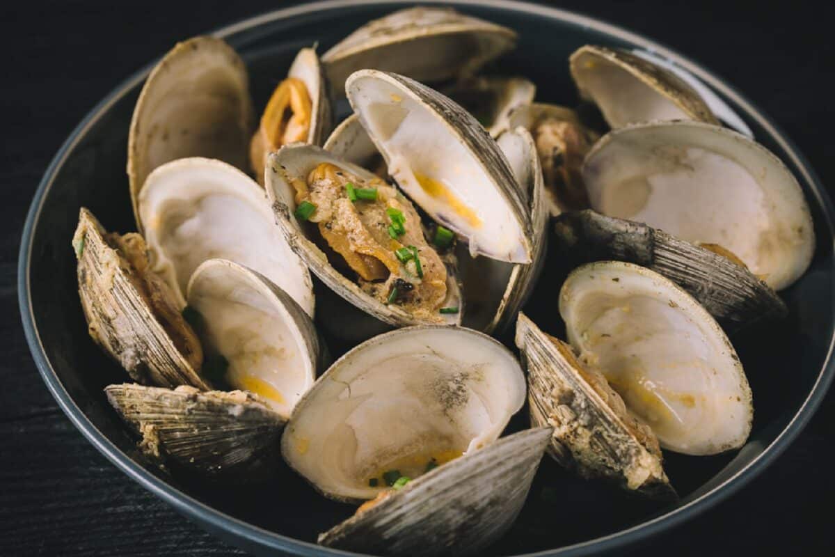 Grilled clams in a black bowl.