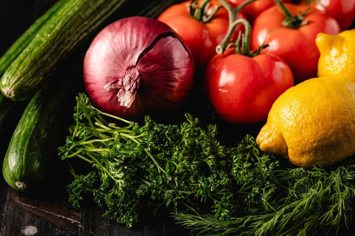 Fresh tomatoes, cucumbers, lemons, onion, and herbs.