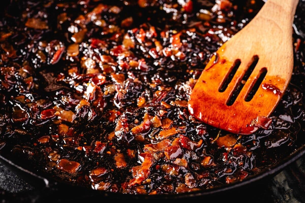 A wooden spatula stirring  pork in a skillet.