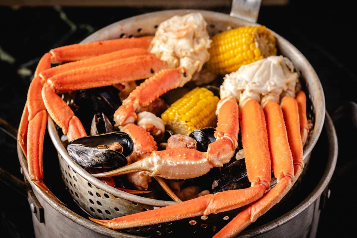 Crab legs, corn, and other ingredients piled in a pot.