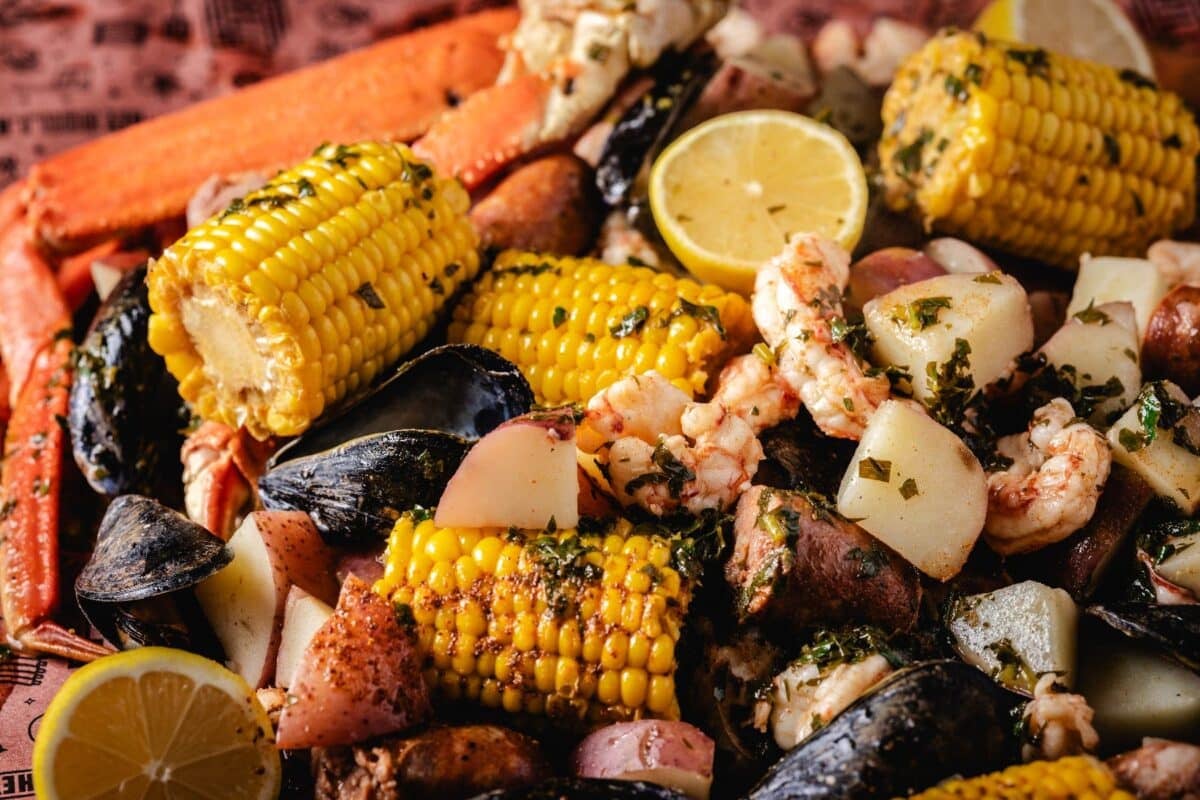 A platter of various boiled seafoods, corn, and potatoes.