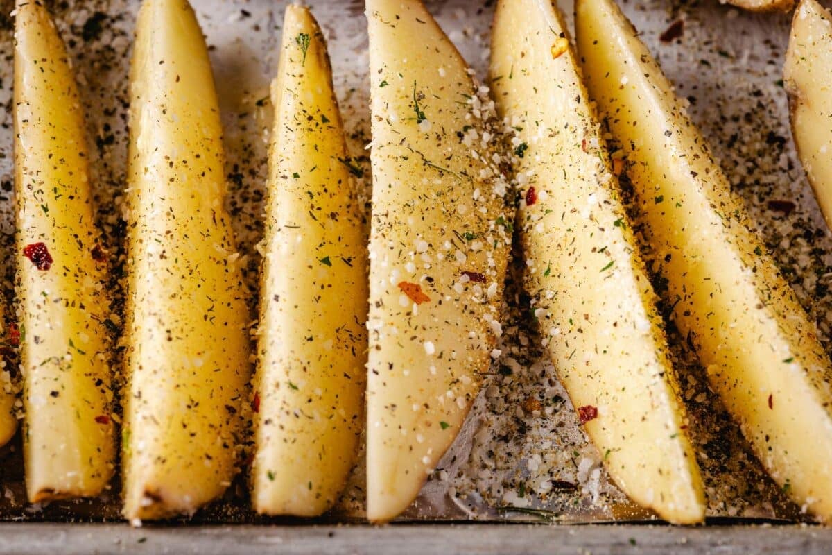 Potato wedges on a baking sheet sprinkled with ranch seasoning.