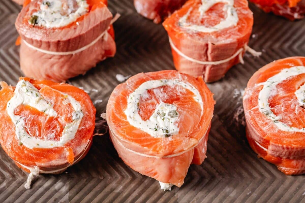 Strips of salmon rolled with cream cheese, sitting on a baking sheet.