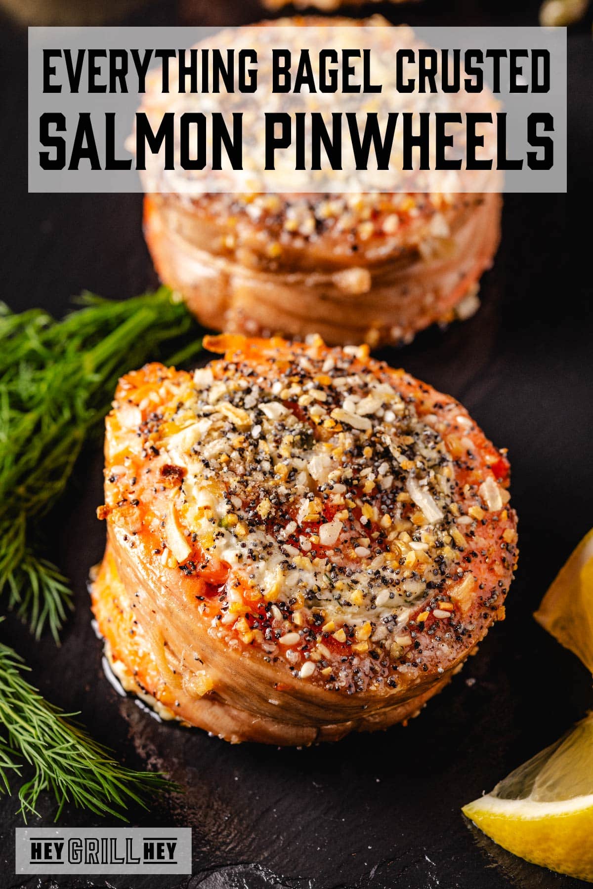 Salmon pinwheels on a black plate. The text overlay reads "Everything Bagel Crusted Smoked Salmon Pinwheels" at the top, and "Hey Grill Hey" at the bottom.