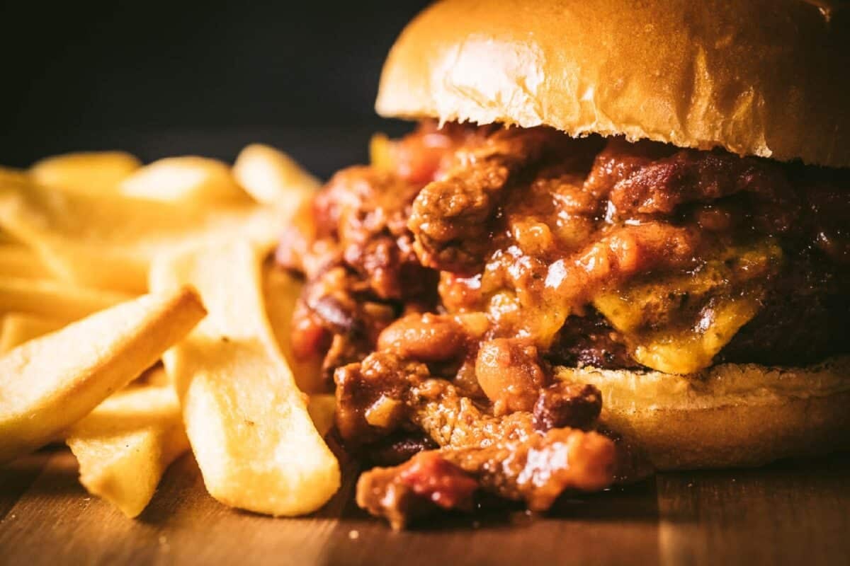 A homemade chili cheeseburger and French fries on a tabletop. 