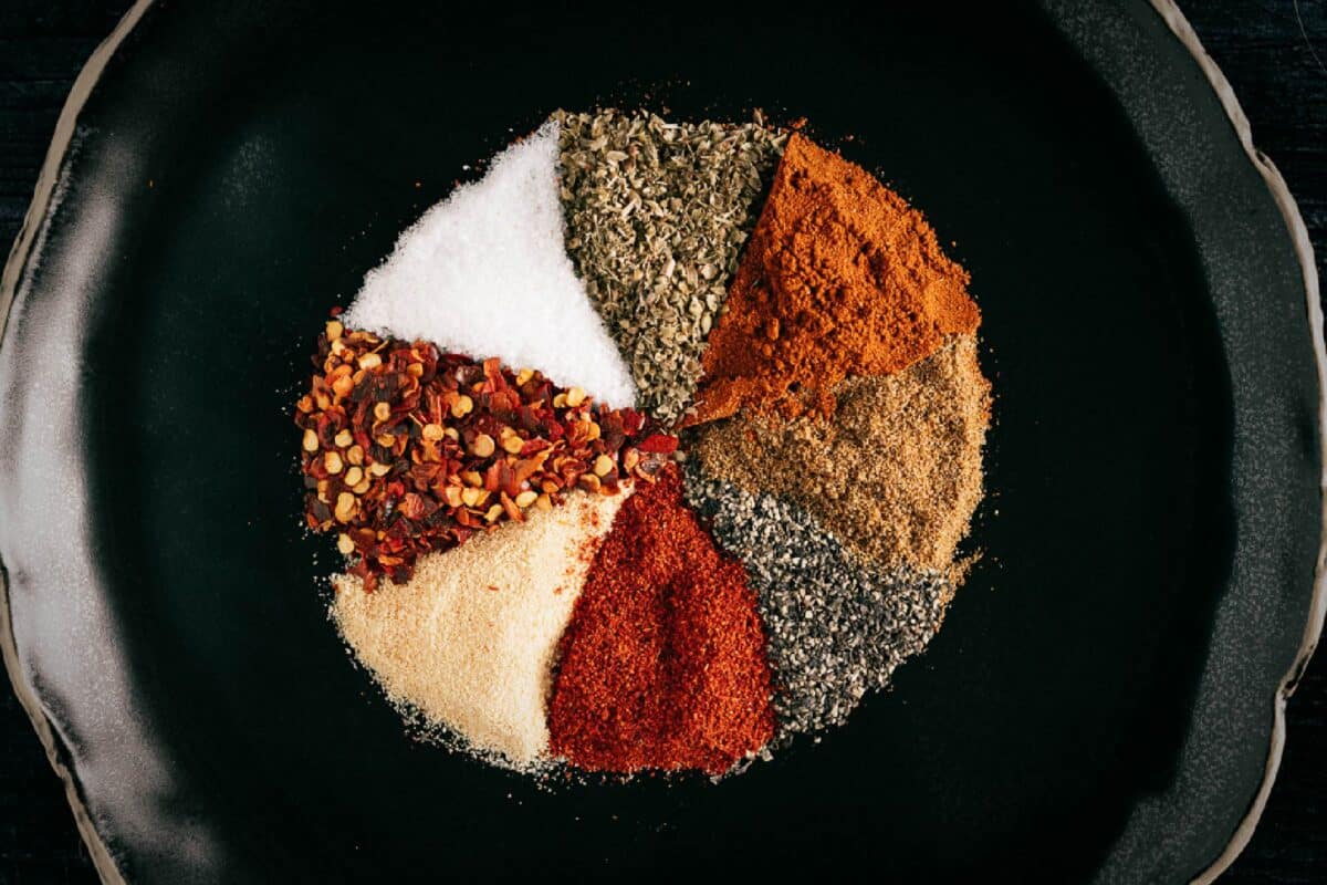 A black plate with 8 spices arranged in triangles.