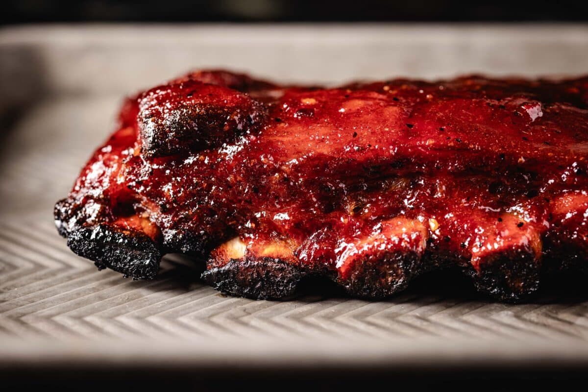 A close-up shot of the exposed bones on a rack of ribs on a baking sheet.