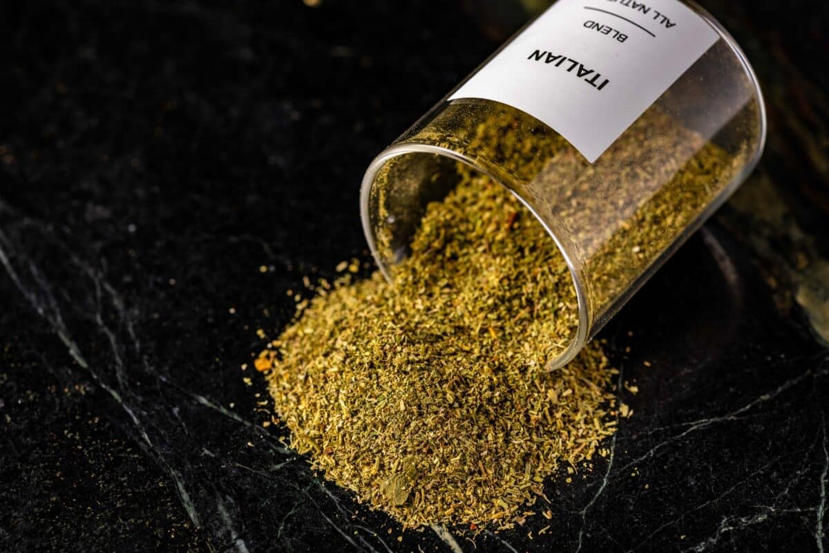 A clear jar of seasoning spilling out onto a black surface.