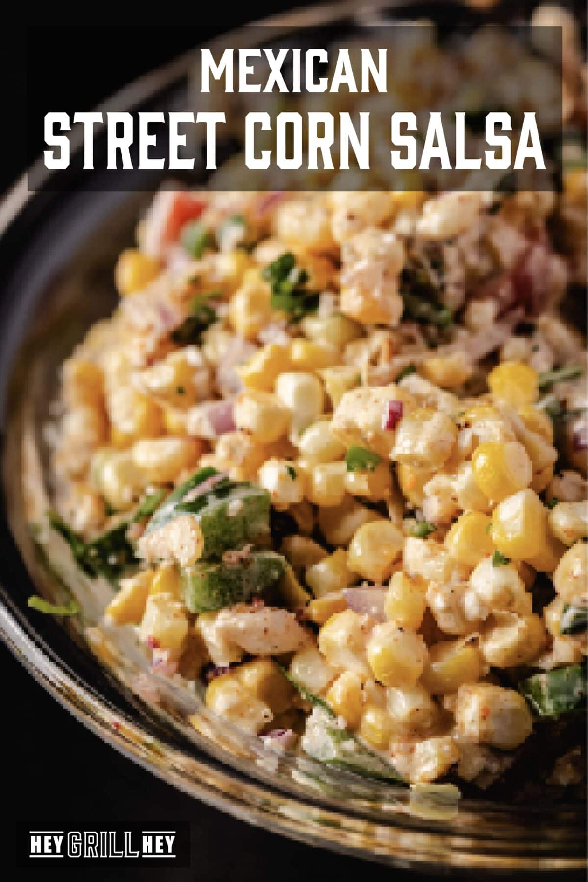 A clear bowl filled with creamy corn, diced tomatoes, and chopped cilantro. The text overlay reads "Mexican Street Corn Salsa" at the top, and "Hey Grill Hey" at the bottom.