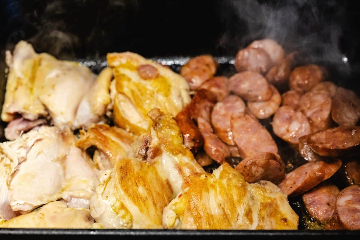 Chicken and sausage in a cast iron pan.