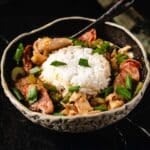A bowl of one-pan gumbo with a scoop of rice and a spoon resting in it.