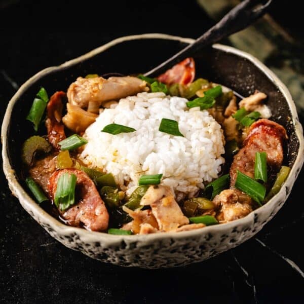 A bowl of one-pan gumbo with a scoop of rice and a spoon resting in it.