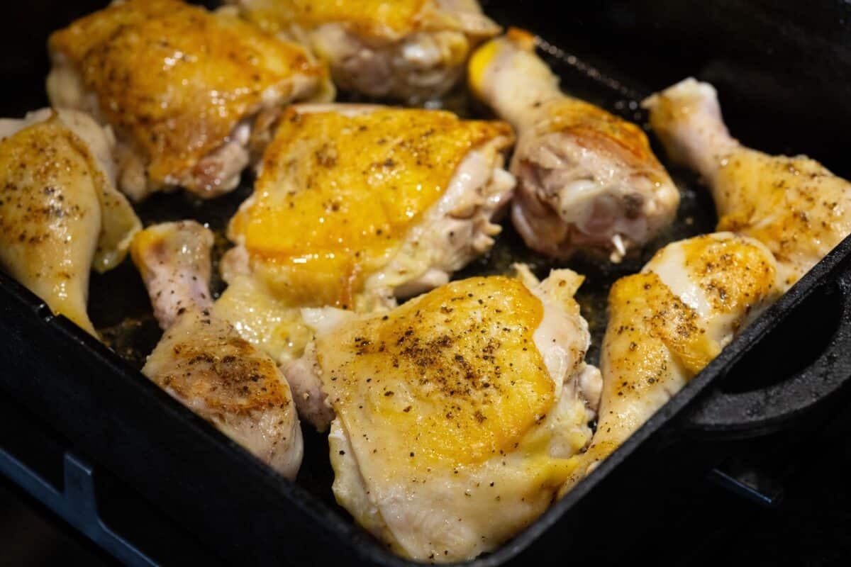 Various cuts of seasoned chicken in a cast iron pot.