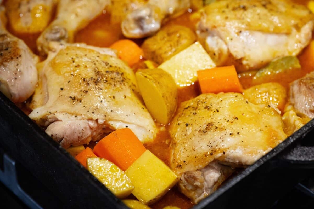 Chicken with chopped carrots and potatoes in a pot.