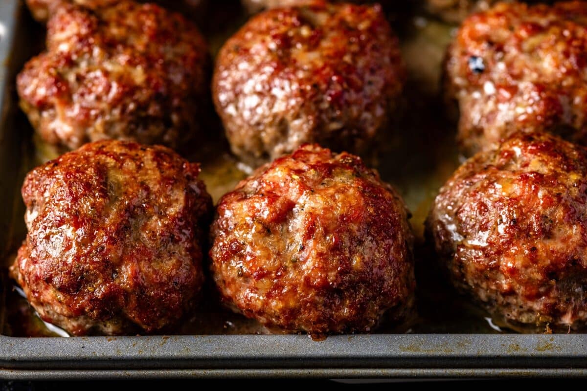 A baking sheet lines with cooked meatballs.