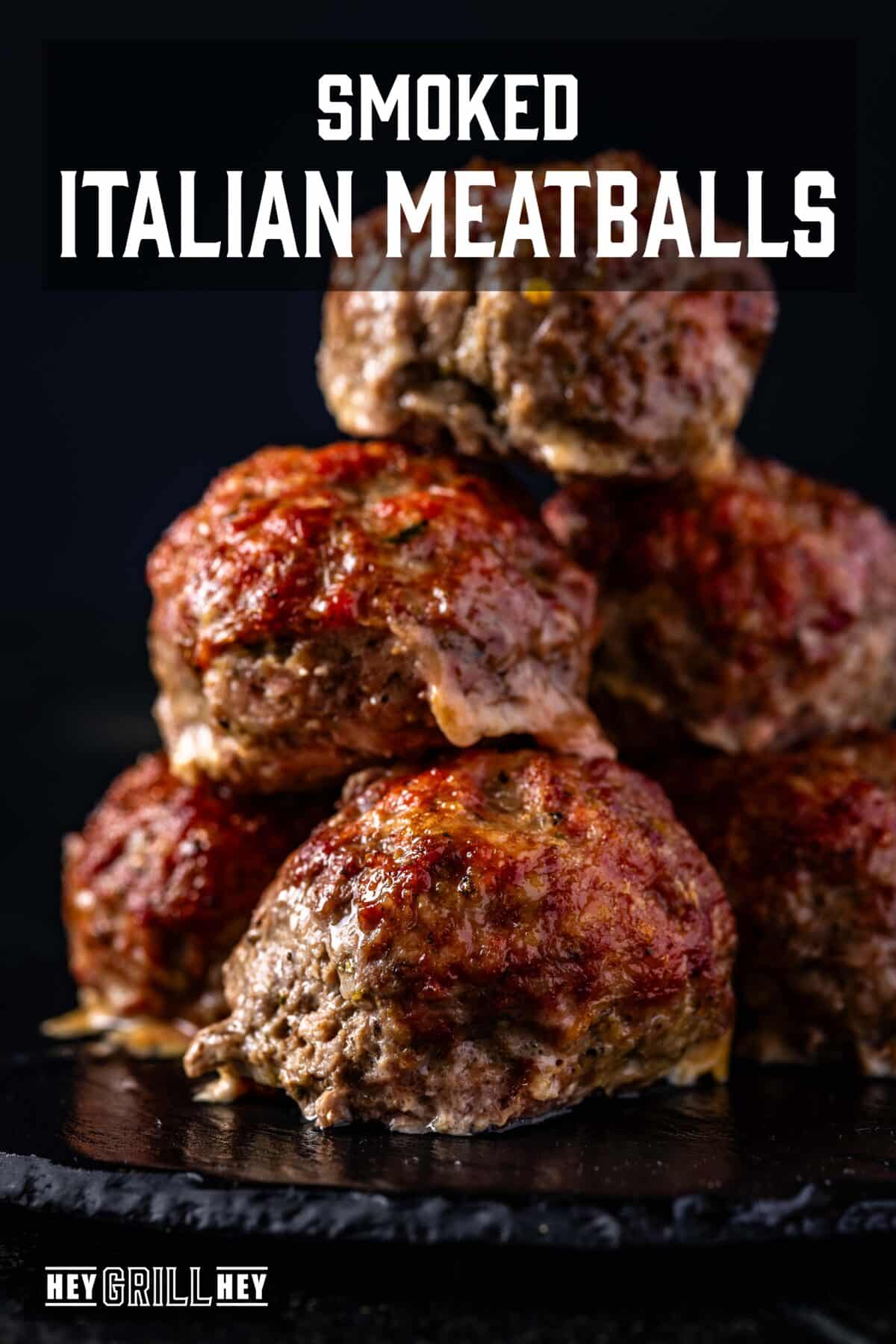 Meatballs piled on a black surface. The text overlay reads "Smoked Italian Meatballs" at the top, and "Hey Grill Hey" at the bottom.