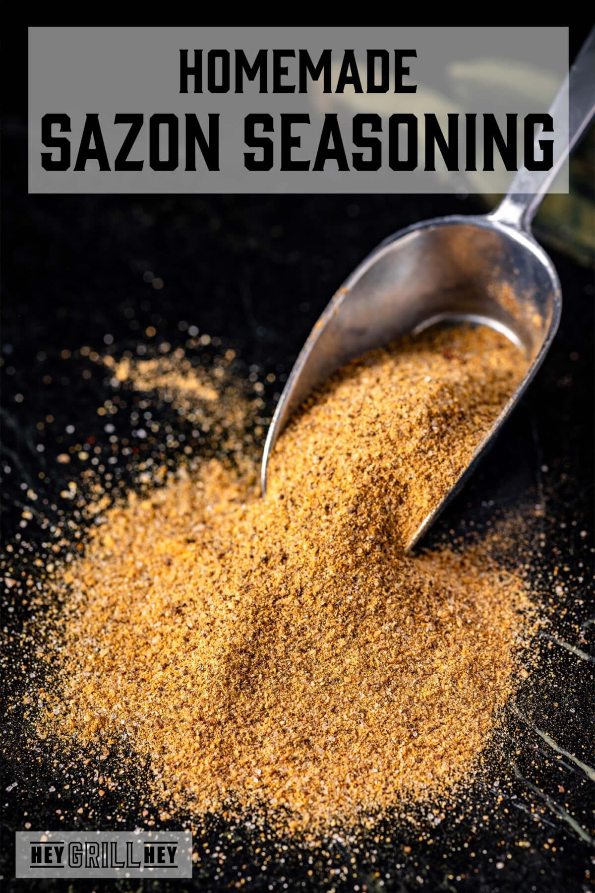 A pile of seasoning with a metal scoop in it. The text overlay reads "Homemade Sazon Seasoning" at the top, and "Hey Grill Hey" at the bottom.