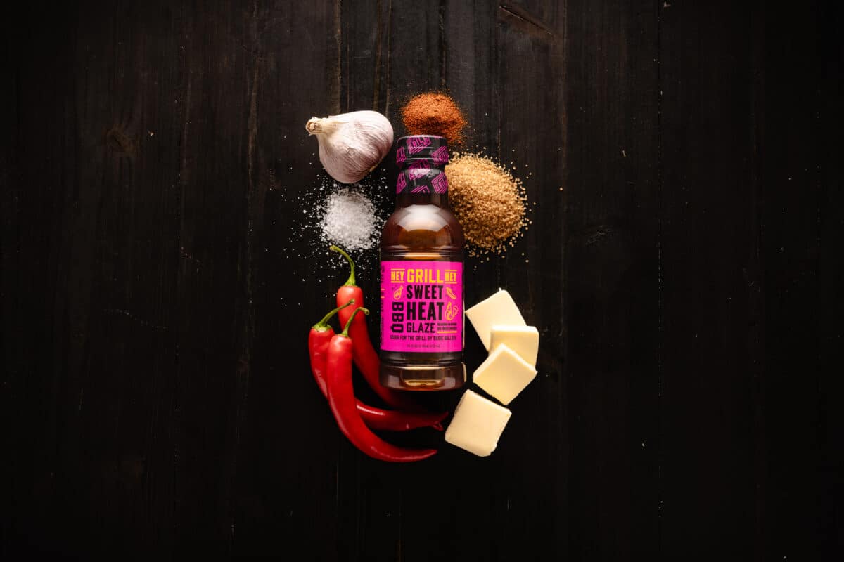 A bottle of Sweet Heat Glaze on a table surrounded by the raw ingredients for the glaze.