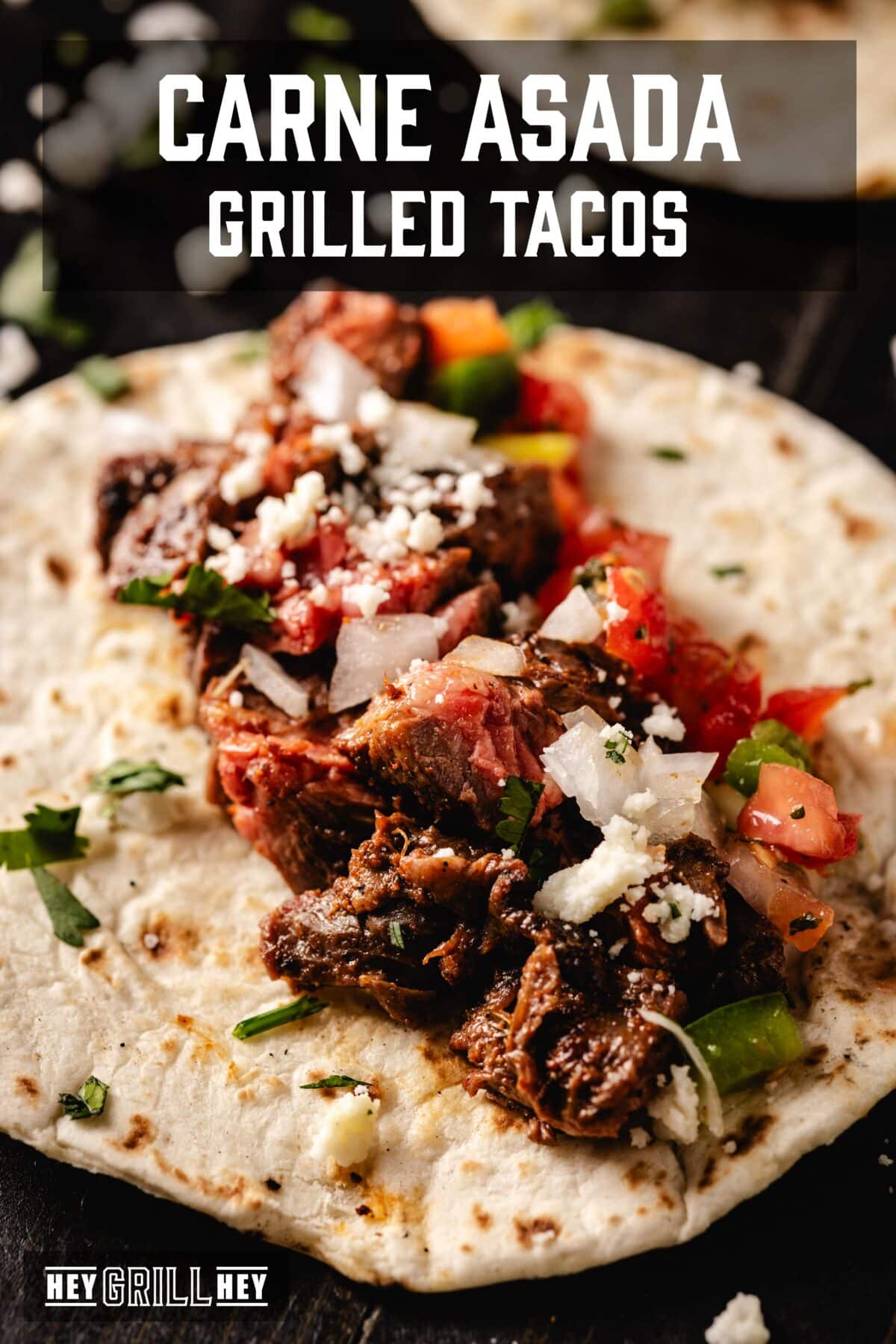 A tortilla topped with carne asada meat, salsa, and shredded cheese. The text overlay reads "Carne Asada Grilled Tacos" at the top, and "Hey Grill Hey" at the bottom.