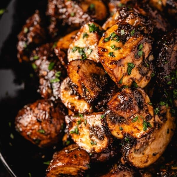 Marinated mushrooms piled on a black plate.