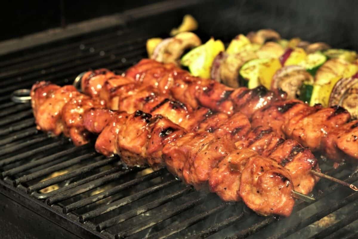 Grilled pork kabobs and vegetables kebabs on the grill grate.