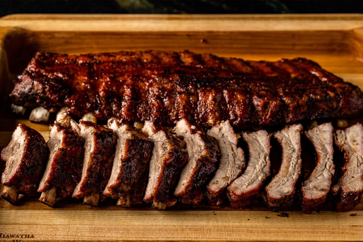A rack of baby back ribs on a cutting board that have been cut into individual ribs for serving.
