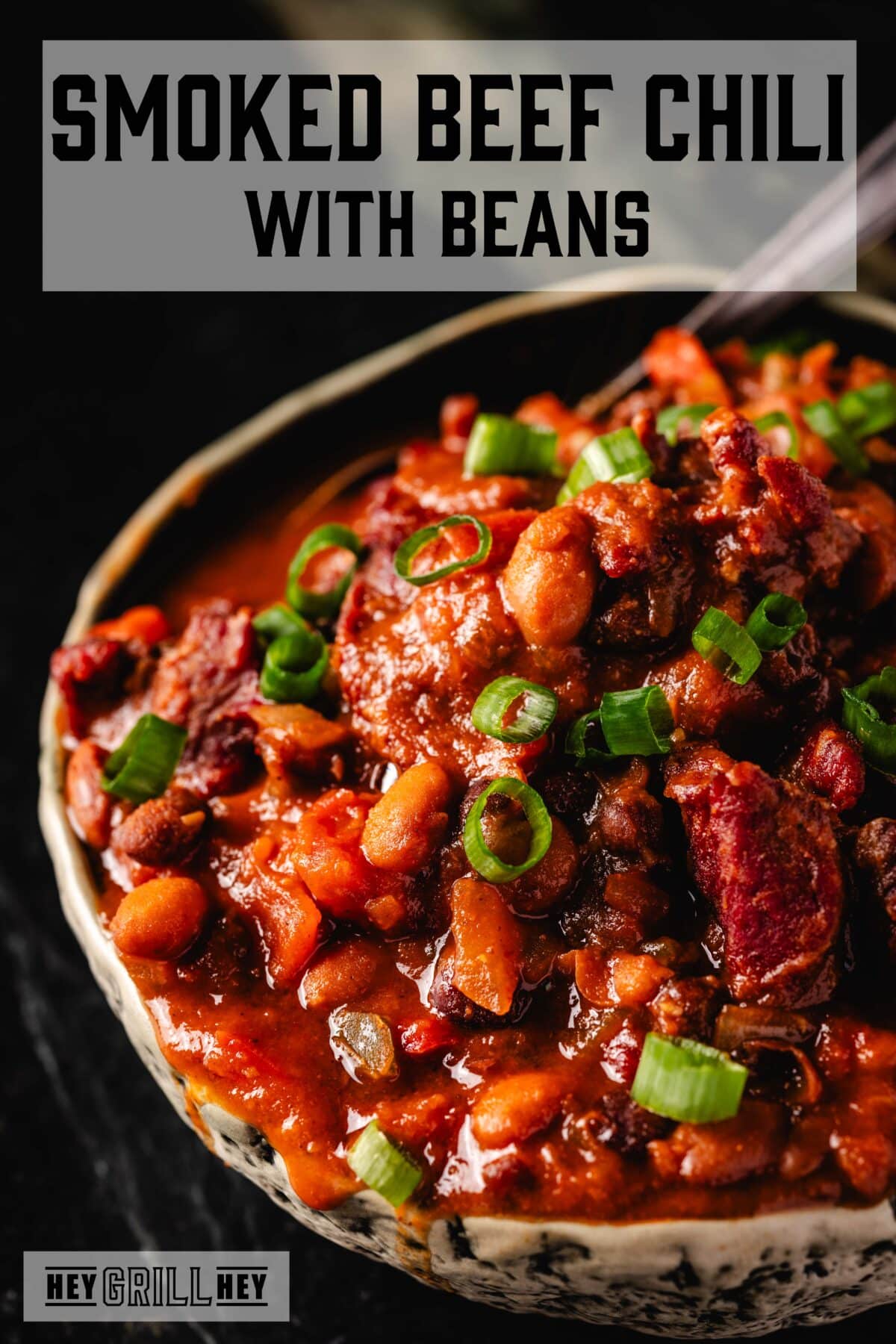 A bowl of beef chili topped with green onions. The text overlay reads "Smoked Beef Chili with Beans" at the top, and "Hey Grill Hey" at the bottom.