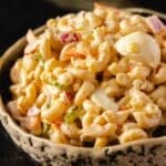 A bowl of tuna macaroni salad with chopped eggs and veggies.