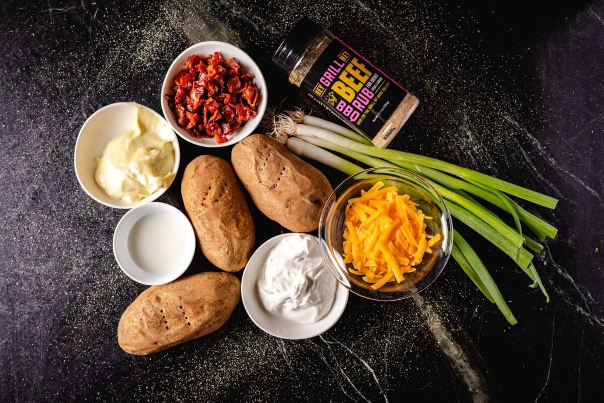 An overhead shot of raw russets and green onions next to bowls of ingredients and a bottle of Hey Grill Hey Beef Rub.