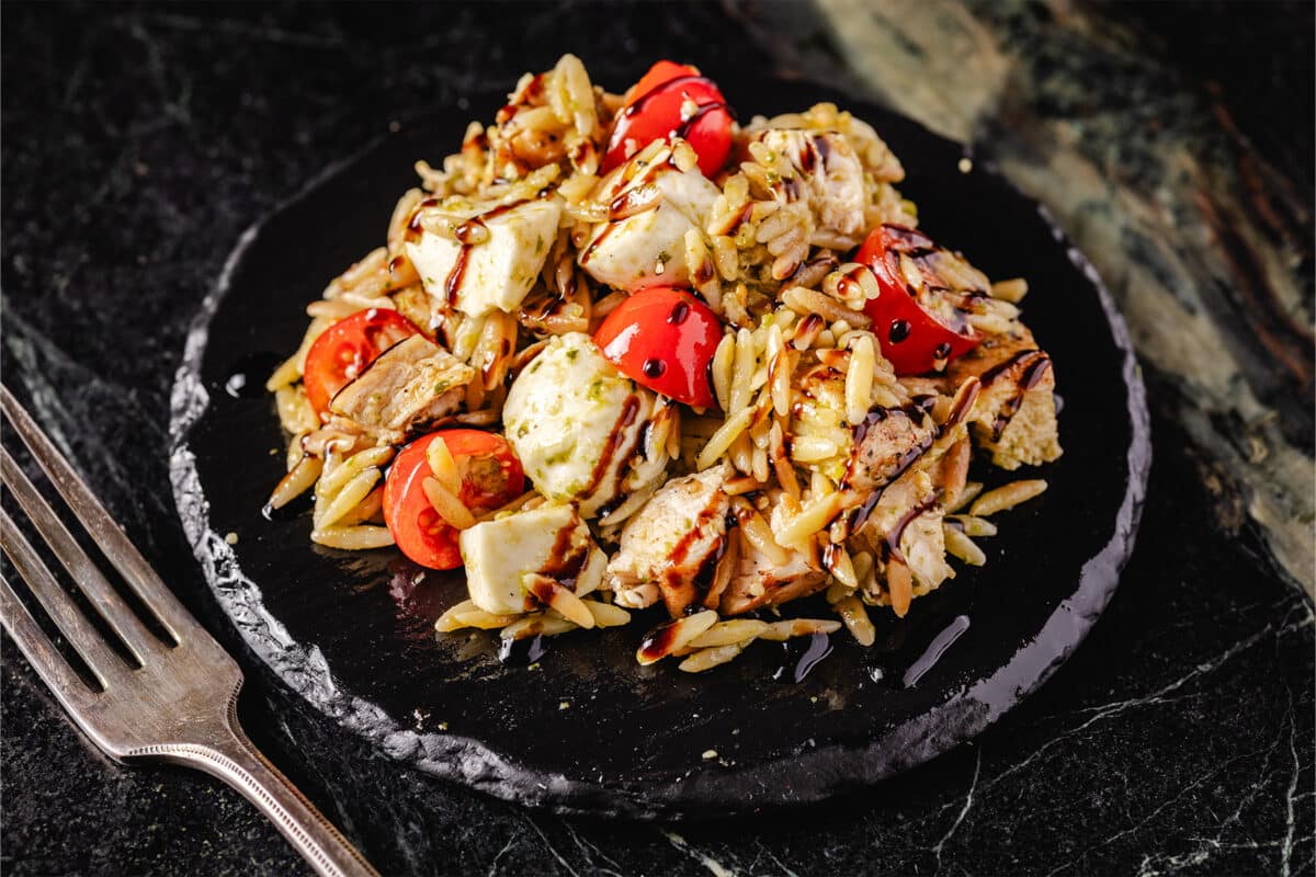 A black bowl filled with chicken orzo salad in a black bowl.