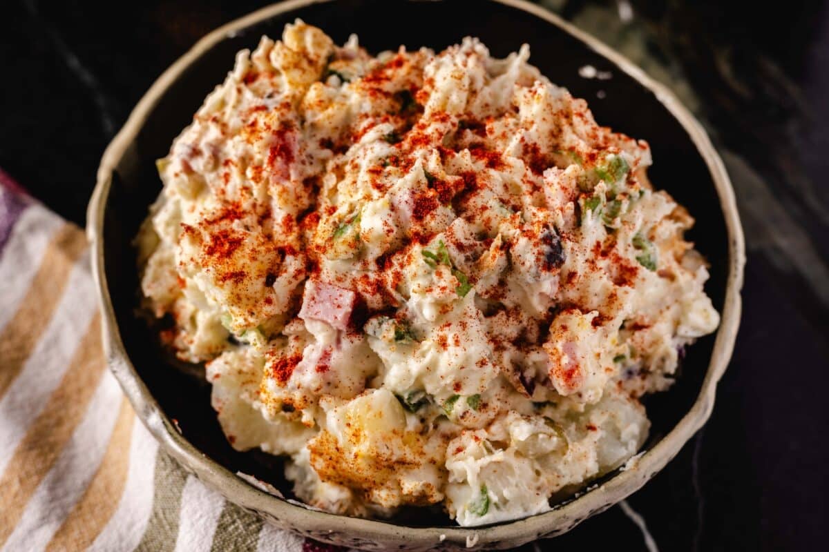 A cold potato salad in a bowl sprinkled with paprika.