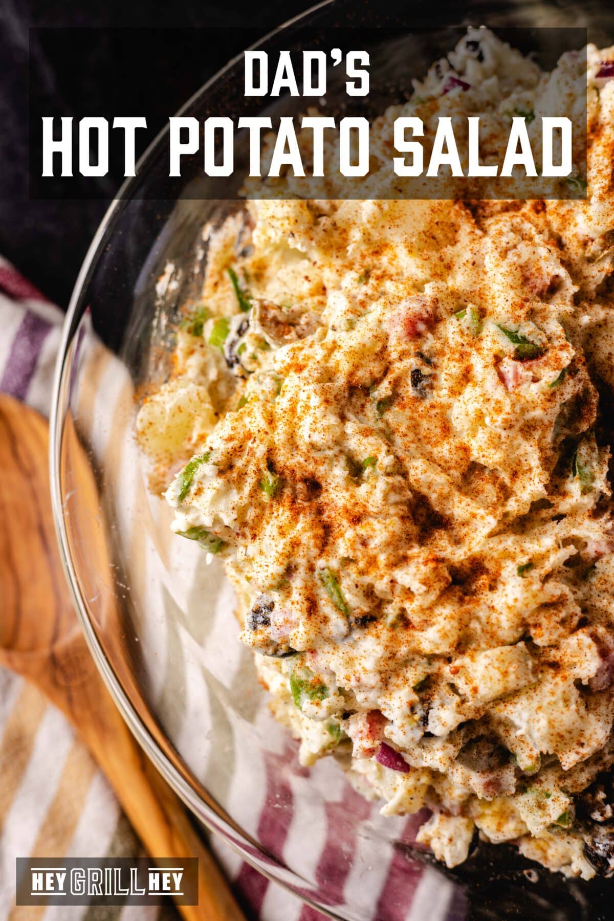 A bowl of salad next to a tablecloth and a wooden spoon. The overlap of the text reads "Dad's hot potato salad" above, e "Hey Grill Hey" in conclusion.