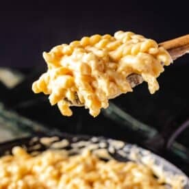 Gemelli pasta on a wooden serving spoon held above a skillet of the dish.
